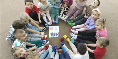 dzieci siedza pokazując swoje kolorowe skarpetki