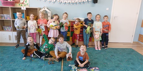 dzieci stoją trzymojąc zabawowe dinozaury