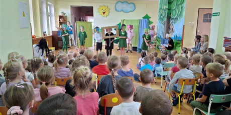 na pierwszym planie dzieci ogladajace teatrzyk. Na drugim planie dzieci, przebrane w stroje słoni, prezentujący sztukę